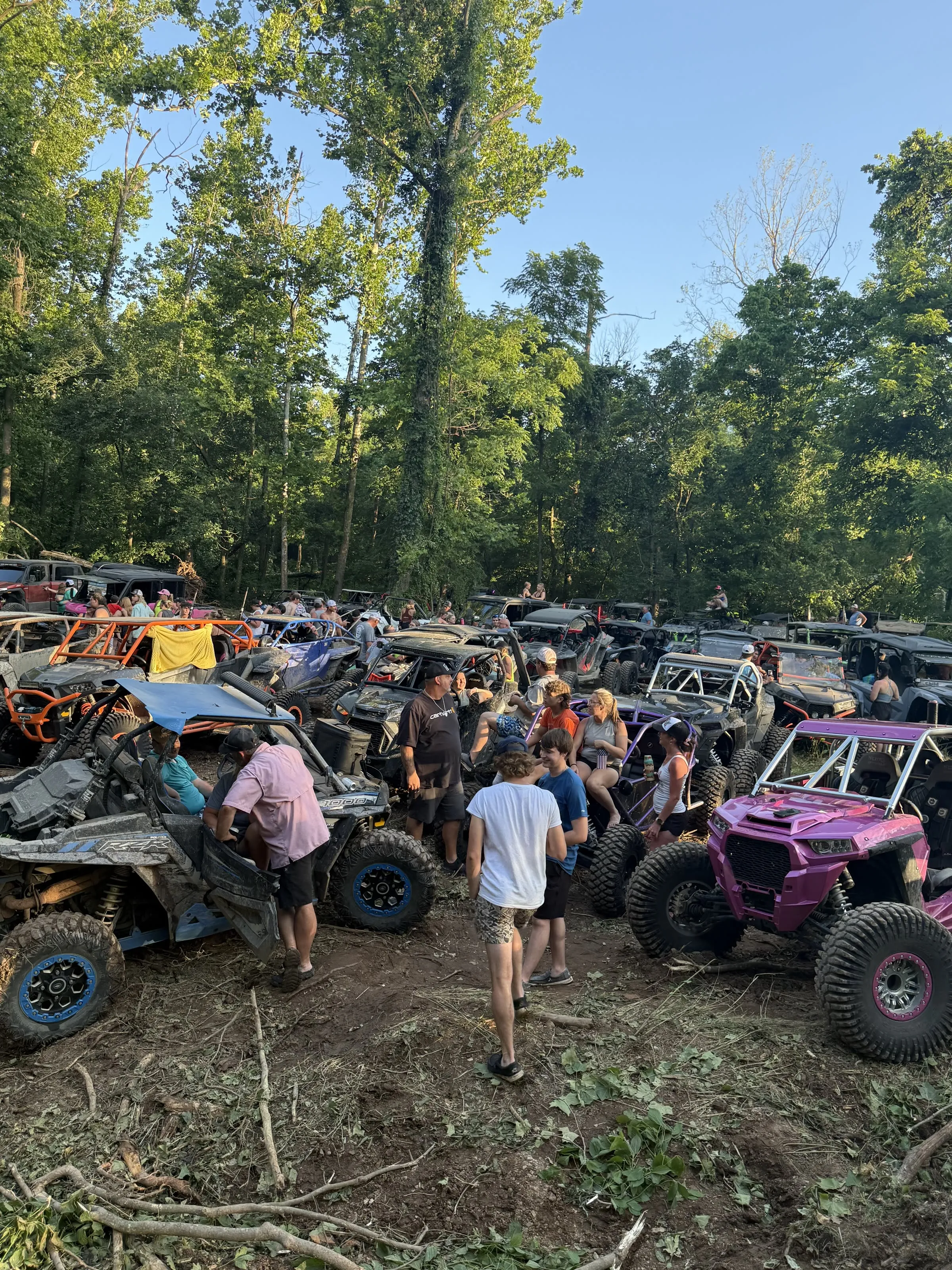 Riders gathered among a colorful lineup of UTVs at camp in the evening light