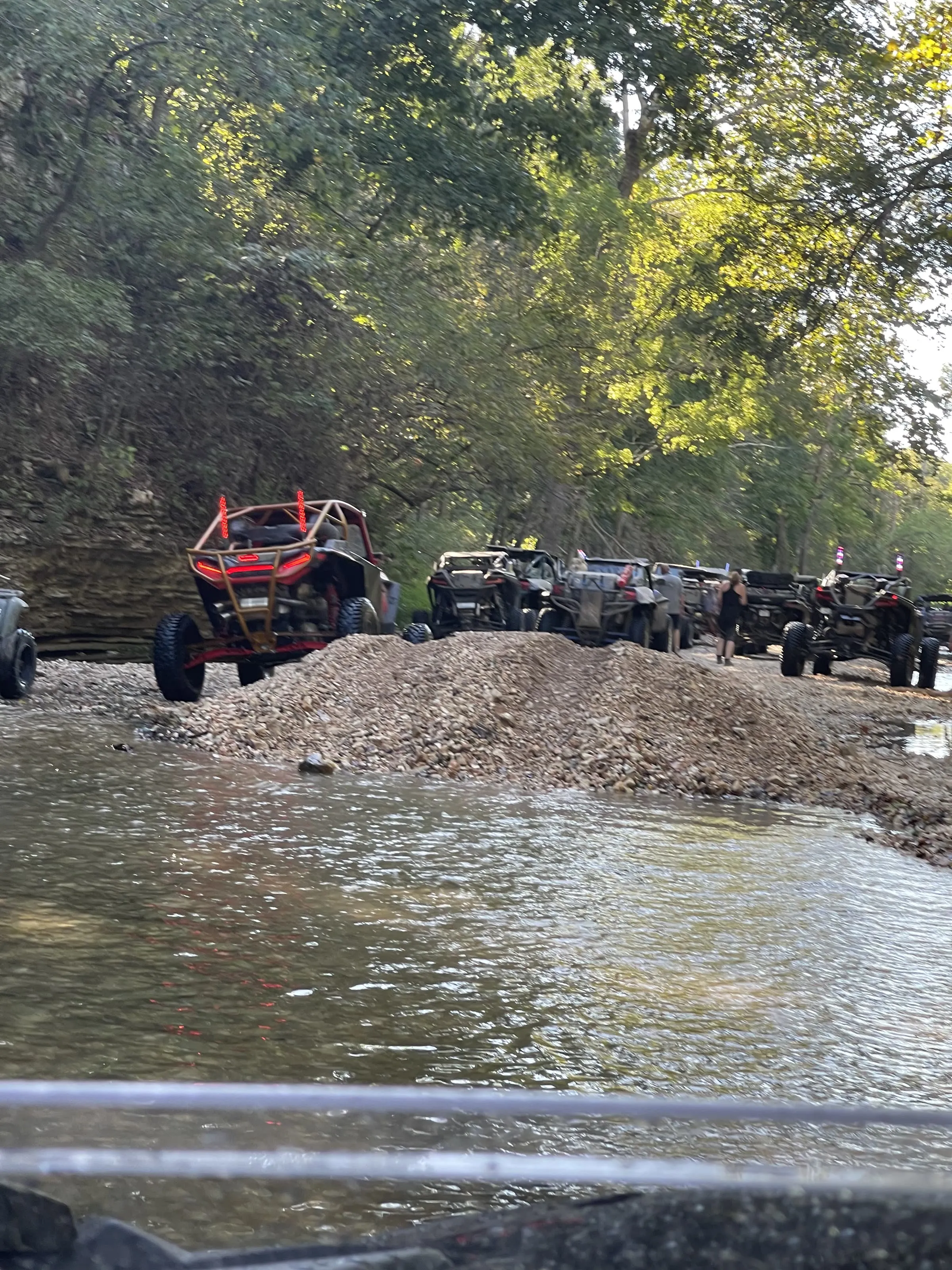 A line of UTVs crossing the creek together at dusk