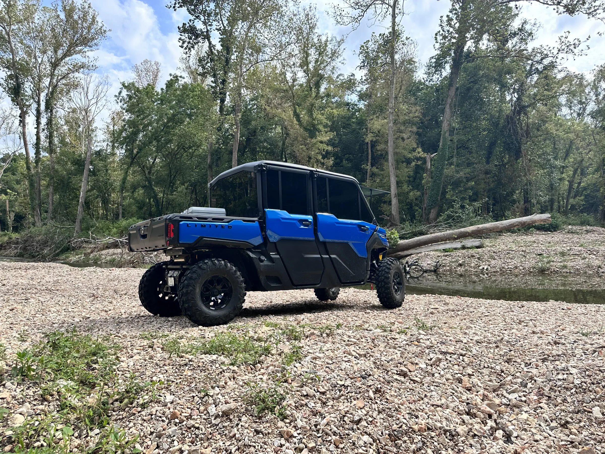 A UTV parked on a wide gravel bar at a creek bend