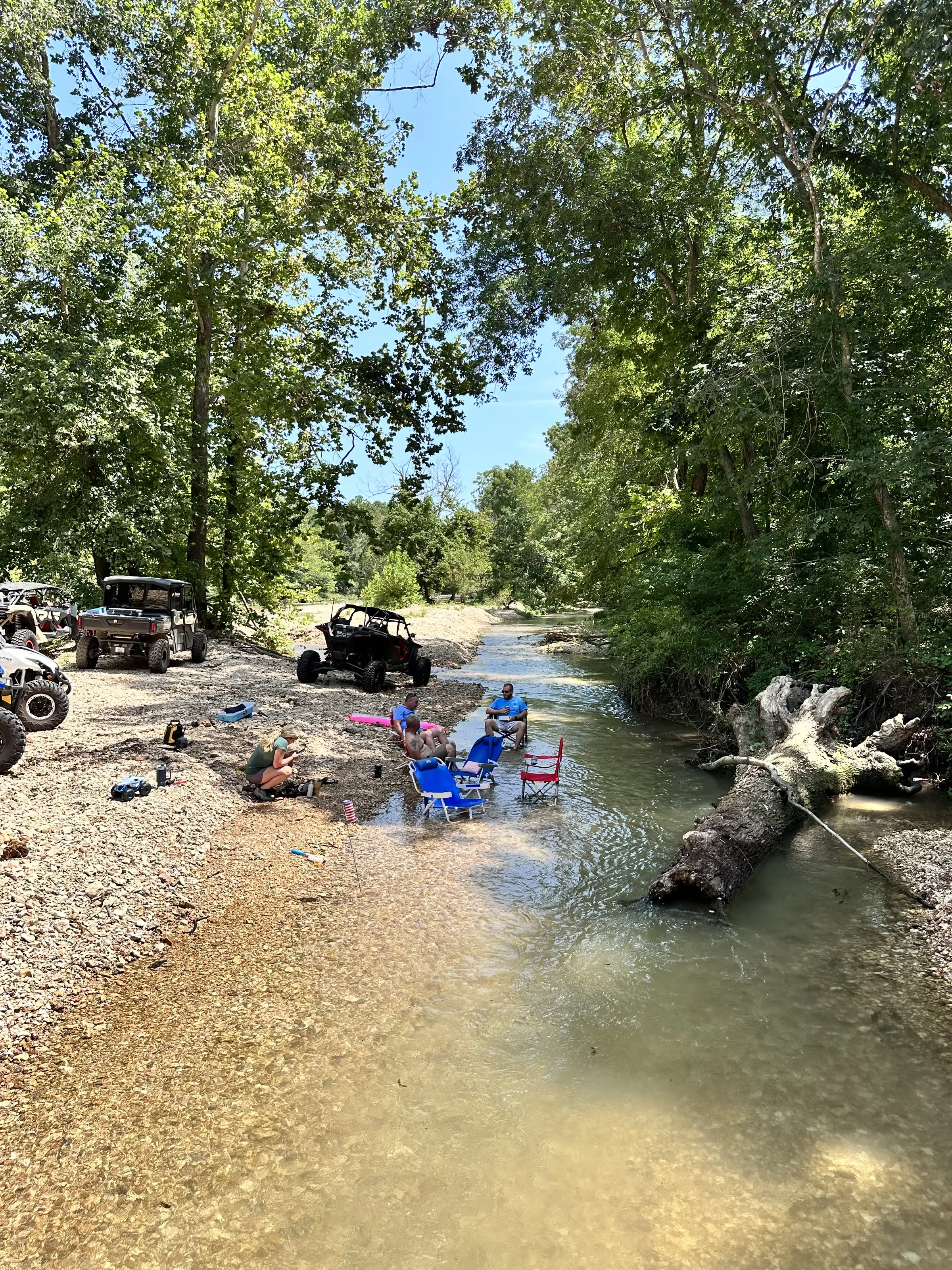 Camp friends relaxing in chairs set up right in the creek