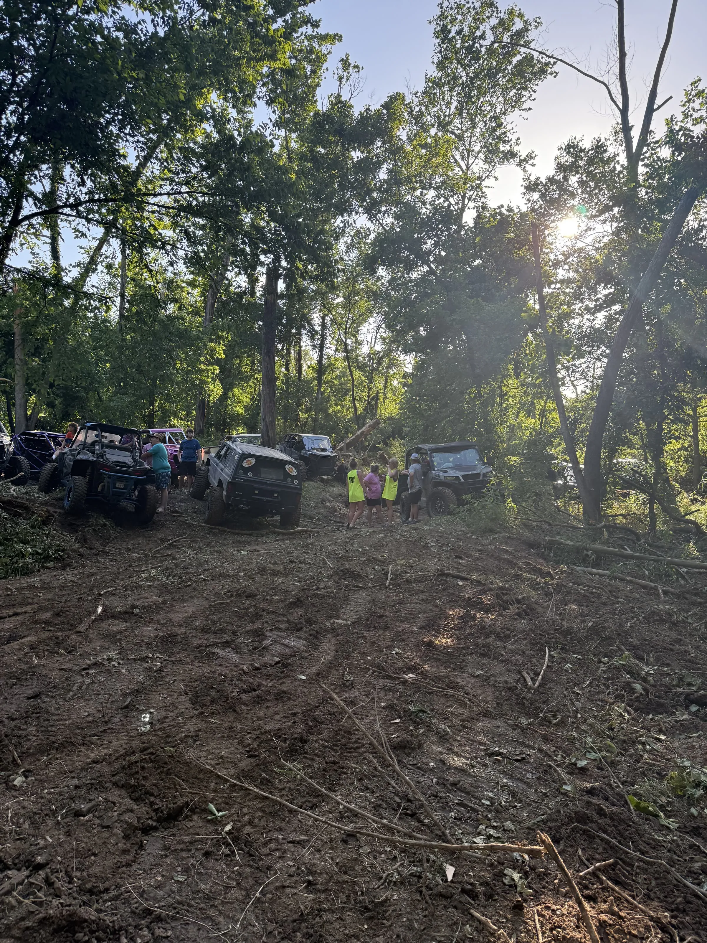 A group of riders and rigs gathered on a muddy hilltop trail
