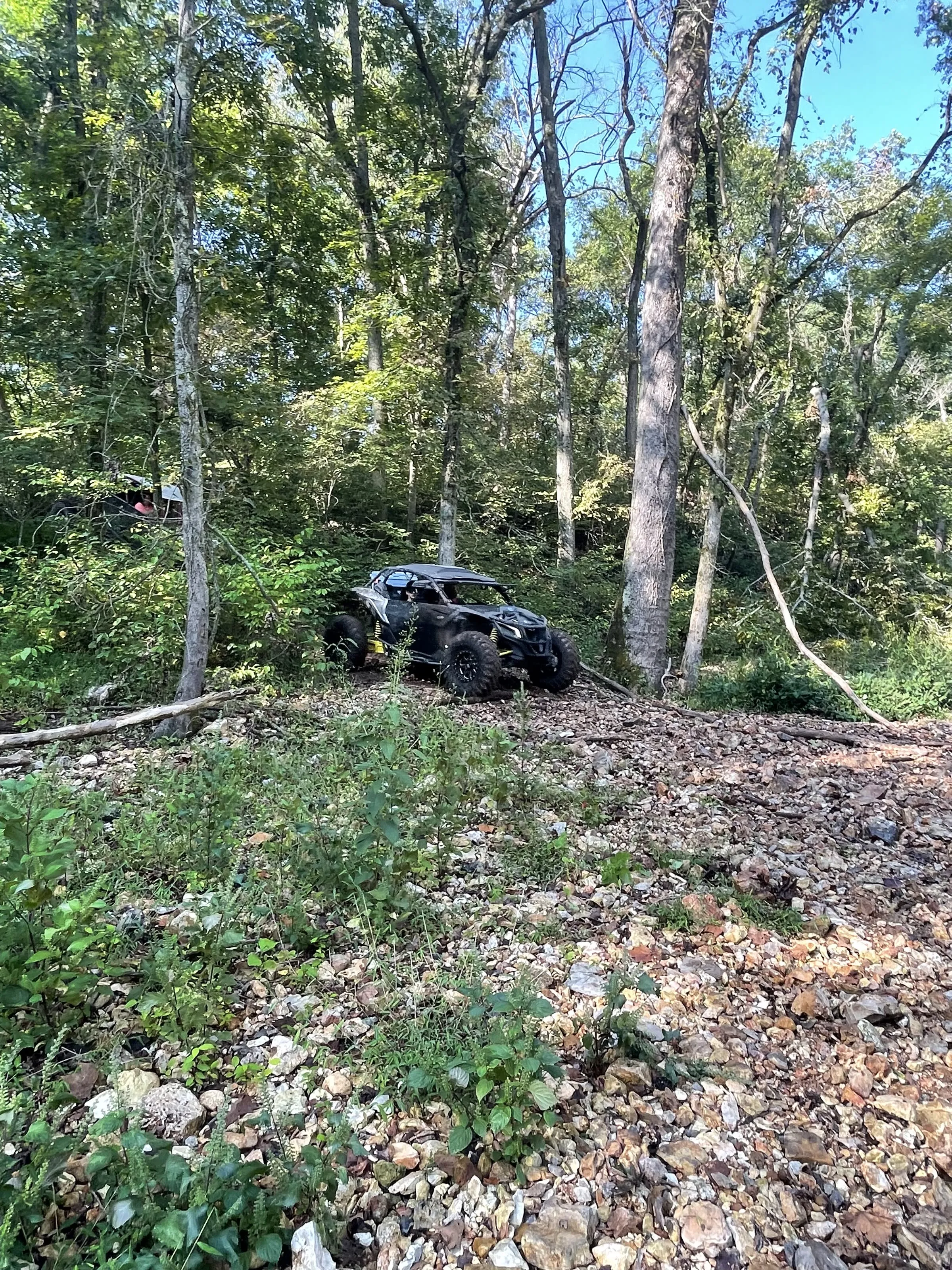 A UTV navigating a rocky wooded hillside trail