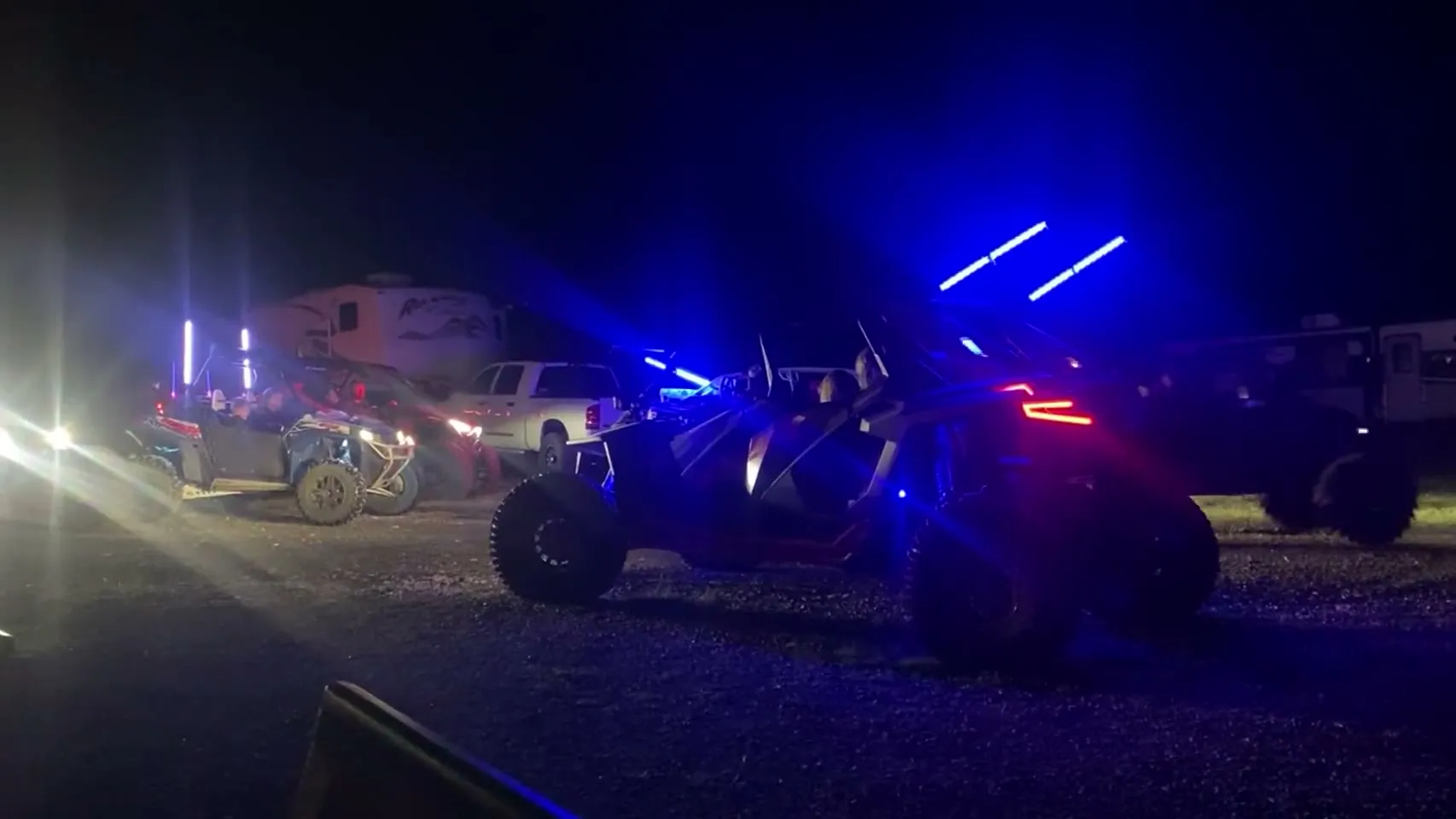 UTVs with blue lights gathered at camp at night