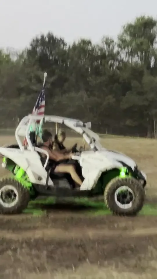 A UTV with purple underglow and an American flag riding at dusk