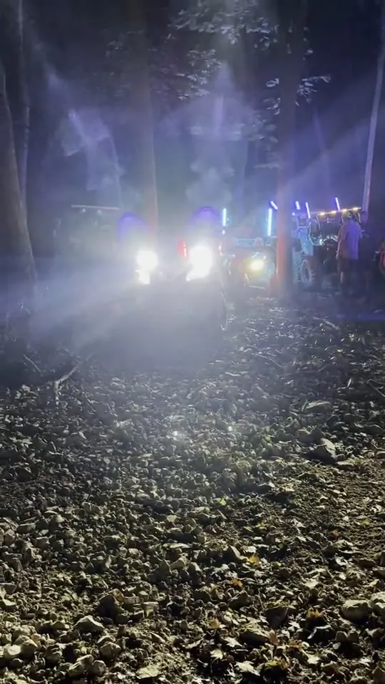 A UTV with glowing red taillights on a dark trail at night