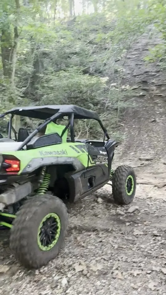 A rider kicking up dust climbing a rocky stair-step trail