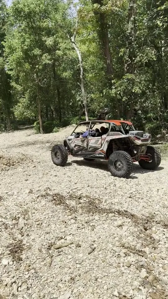 A UTV riding along a gravel trail through the trees