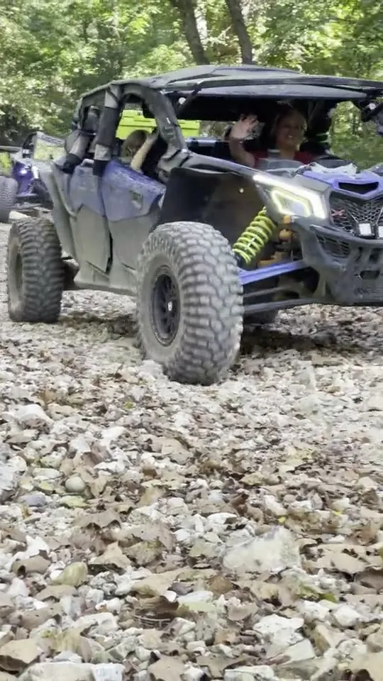A UTV with purple LED lights approaching down a rocky trail